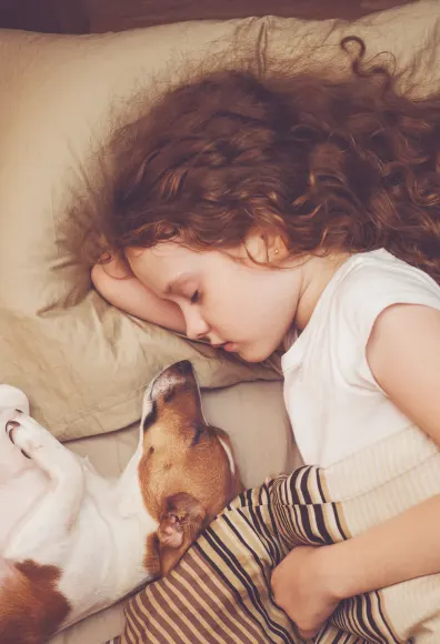 girl sleeping in bed with dog